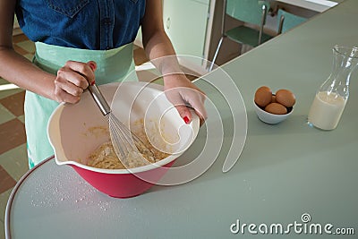 Young woman whisking mixture into bowl in the kitchen Stock Photo