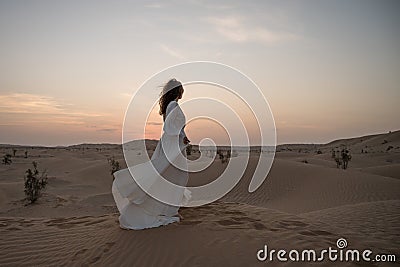 Young woman in white bridal dress alone in desert Stock Photo