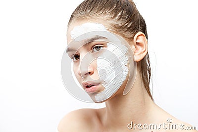 Young woman with a white cosmetic mask on a half of her face on the white background Stock Photo