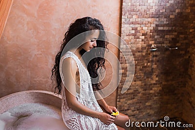 Woman in white lingerie relaxing near stone bath full foam in moroccan bathroom Stock Photo