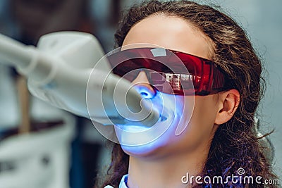 Young woman whiten teeth at the dentist. Close up view Stock Photo