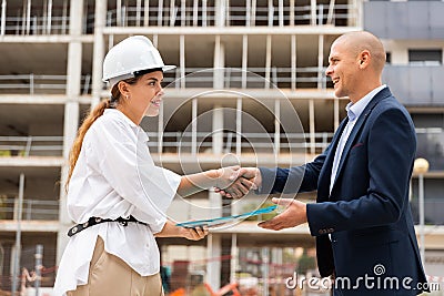 Young woman working as a process engineer, friendly shakes hands with a male customer Stock Photo