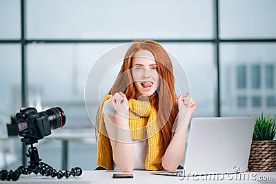 Young woman working on computer with cameras and accessories on table. Stock Photo