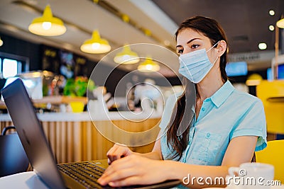 Young woman working on laptop, wearing protective face mask.Online training education and freelance work.Studying remotely. Stock Photo