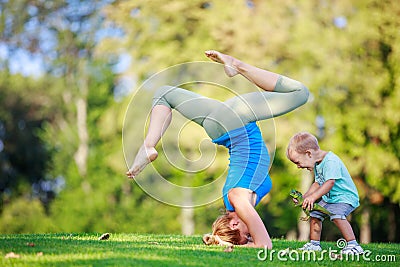 Young woman working out outdoors, little son playing beside her Stock Photo