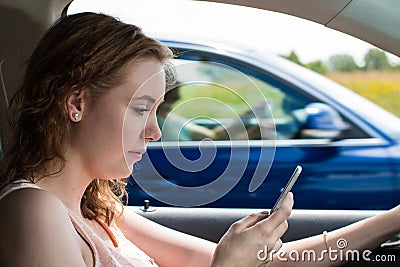 A young woman writes a text message while driving Stock Photo