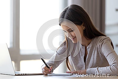 Young woman writing notes in notebook making list planning tasks Stock Photo