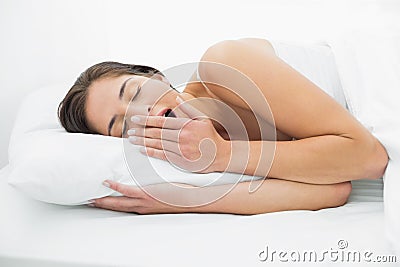 Young woman yawning in bed Stock Photo
