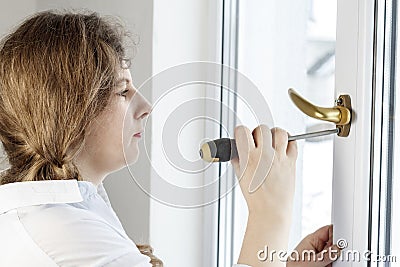 . Young woman 30 years old. unscrew the with a screwdriver. I& x27;m going to fix the pen on the glass Stock Photo