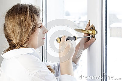 . Young woman 30 years old. unscrew the with a screwdriver. I& x27;m going to fix the pen on the glass Stock Photo