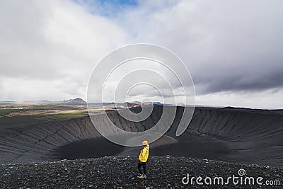 Young woman in yellow raincoat standing in the crater of Hverfjall volcano in Myvatn area, Iceland Stock Photo