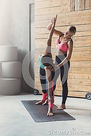 Young woman with yoga instructor in fitness class, triangle pose Stock Photo