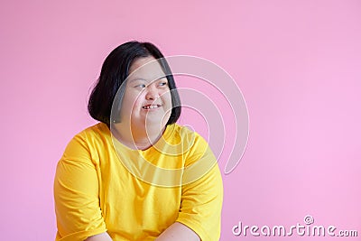 Young women with aphasia or Down syndrome She is a cerebral palsy student wearing a yellow dress on a pink background - Down Stock Photo