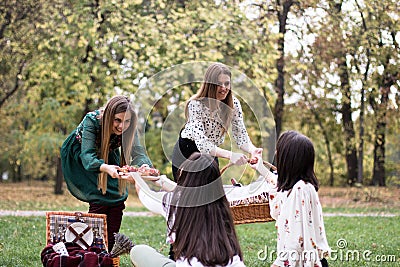 Young women arriving to a picnic, bringing food and drink to their friends Stock Photo