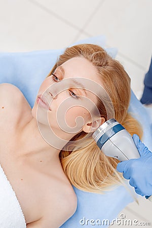 Cosmetology Service. Young woman at beauty clinic lying while doctor using body contouring coolwaves system on face Stock Photo