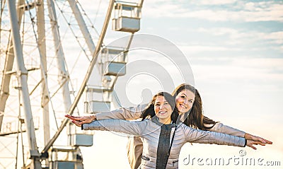 Young women best friends enjoying time together outdoors at ferry wheel Stock Photo