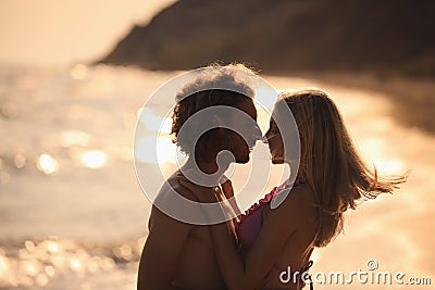 Young woman in bikini her boyfriend on beach at sunset. Lovely couple Stock Photo