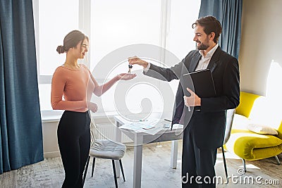 Young woman buy rent apartment. She get keys from realtor. Happy and joyful. Business deal in office room. Bright Stock Photo