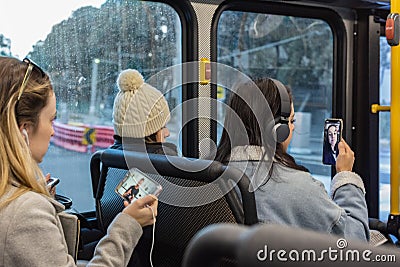 Young women communicate with their mobile devices on bus Editorial Stock Photo