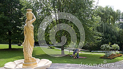Young women doing yoga outdoors. Background of a beautiful public park in summer Editorial Stock Photo