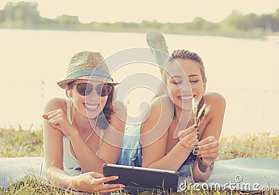 Young women friends laughing watching social media blogs on pad computer Stock Photo