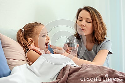 Young woman giving pill for her ill daughter in bed Stock Photo