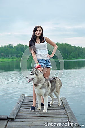 Young women and her dog husky resting near lake in summer Stock Photo