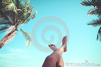 Young women lying on a tropical beach, relax stretching up slender legs tanned. Stock Photo