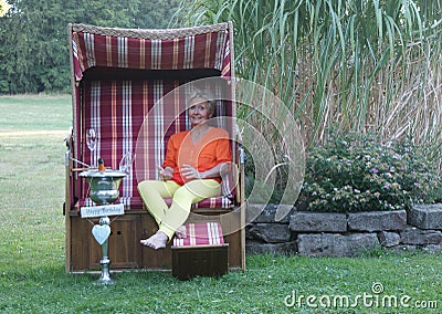 Attractive woman is celebrating her birthday in a roofed wicker beach chair Stock Photo