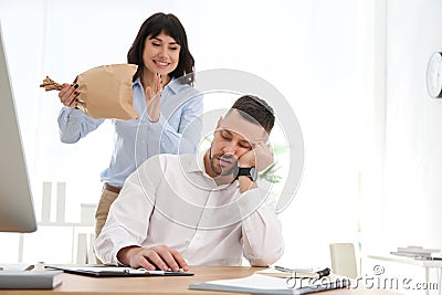 Young woman popping paper bag behind her sleeping colleague. April fool`s day Stock Photo