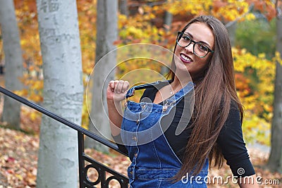 Young women portrait outside autumn leaves overalls glasses Stock Photo