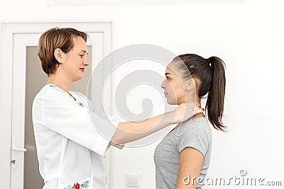 Young woman professional short-haired therapist in a bright medical office, examines a patient, feels the thyroid gland Stock Photo