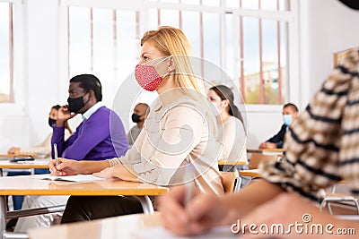 Woman in protective mask listening to lesson in extension school Stock Photo
