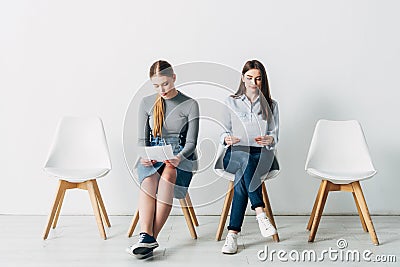 Young women with resume sitting on chairs Stock Photo