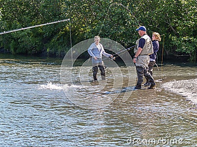 Young women on side of Alaskan river in waders salmon fishing Editorial Stock Photo