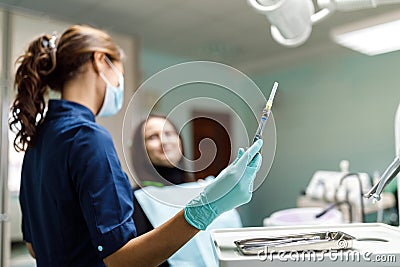 The beautiful young woman is at the dentist. She sits in the dentist`s chair and the dentist carefully examines the patient`s Stock Photo