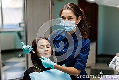 The beautiful young woman is at the dentist. She sits in the dentist`s chair and the dentist carefully examines the patient`s Stock Photo