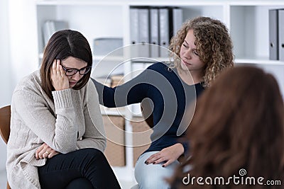 Young woman supporting sad patient at Women`s issues support group Stock Photo