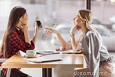 Young women talking while having business lunch meeting in cafe Stock Photo