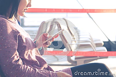 Young women texting on mobile phone waiting for flying at airport window Editorial Stock Photo