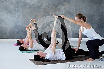 Young women working out doing exercise on floor in Supta Padangushthasana Stock Photo