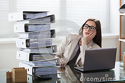 Worried Businesswoman Looking At Folders Stack Stock Photo