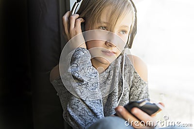Young 10 years woman listening music close to the window Stock Photo