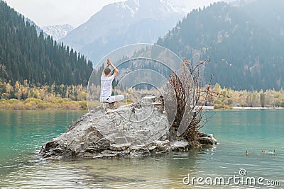 Young zen man in meditation. Outdoor yoga in mountain lake. Exercise Agni Stambhasana Stock Photo