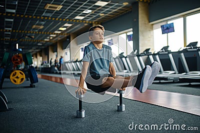 Youngster doing exercise with dumbbells in gym Stock Photo