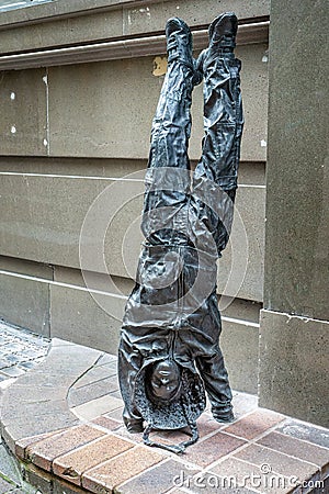 Youngsters - bronze statue of young urchin girl doing a hand stand wearing a hoodie in George Street, Sydney, Australia Editorial Stock Photo