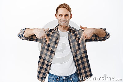 Your advertisement bellow. Smiling handsome redhead man pointing fingers down at logo banner, showing promo text Stock Photo