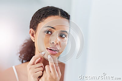 Youre doing more damage than good. a beautiful young woman squeezing a pimple in the mirror. Stock Photo