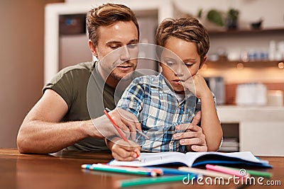 Youre doing well, buddy. a man sitting with his son while he does his homework. Stock Photo