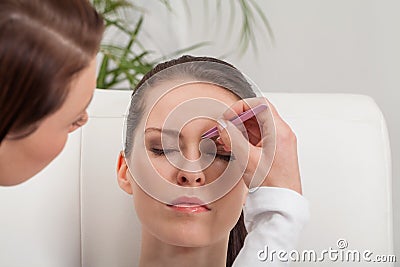 Youtg beautiful woman eyebrow plucking tweezers eyes hair Stock Photo
